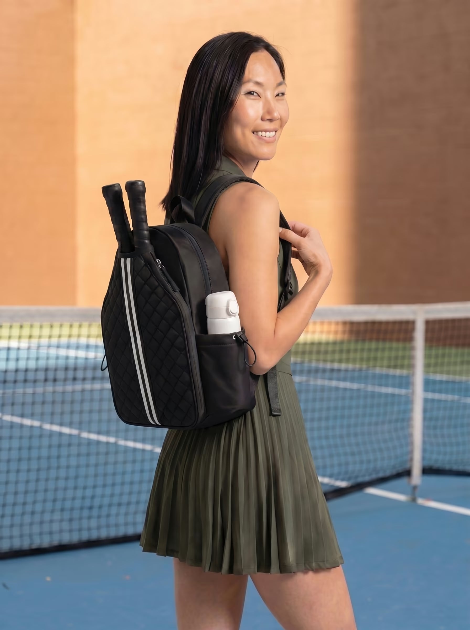 Woman with Rally Cross Body Backpack in Black at outdoor pickleball court