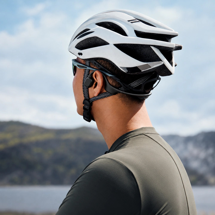 A cyclist wearing Rally Audio under a bike helmet with cycling glasses